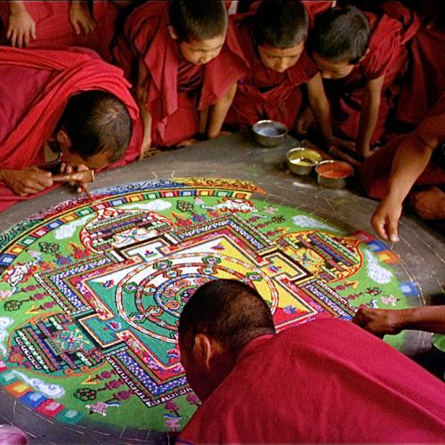 Men and boys leaning over the floor painting a picture.