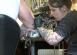 A woman tattooing a burly man's arm