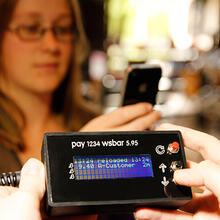 Woman using a phone to make a £B payment at Watershed Bar