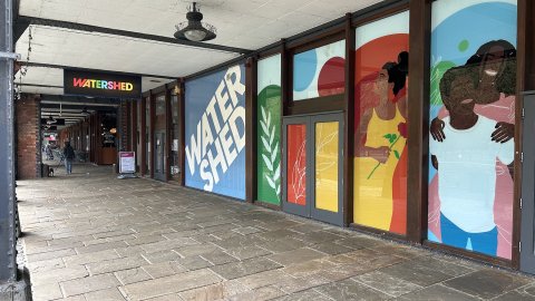 Exterior shot of Watershed front door with murals of people across the glass front.