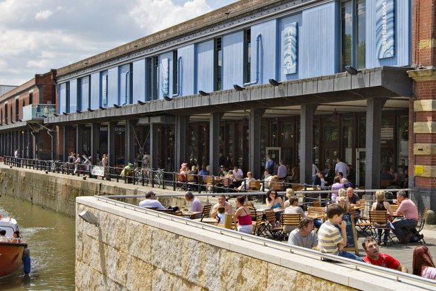 People sat at tables in the sunshine outside the iconic Watershed building on the Bristol harbourside.