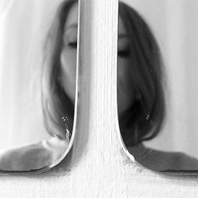 A black and white portrait of Natalia's reflection in two mirrors split in the middle.