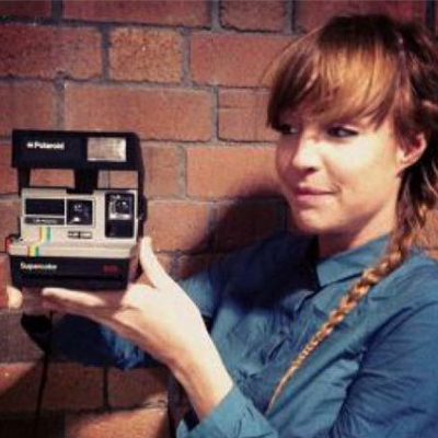 Portrait of Amy's profile. She is holding an old Polaroid camera.