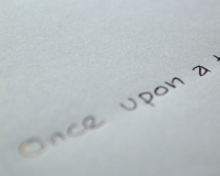 A piece of paper with a pen writing "once upon a time"