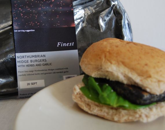 Image of a burger with the supermarket packaging behind it.