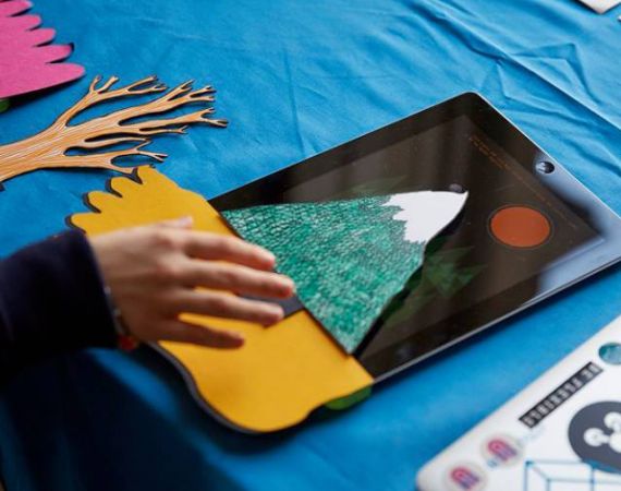 A child's hand using the Bear Abouts paper sensors on an iPad