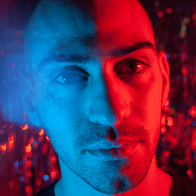A portrait of Alessio with blue and red dramatic lighting.
