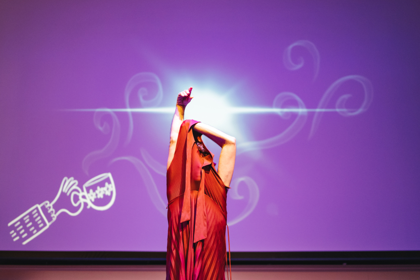 Performer taking a red dress off with bright drawing projected in the background