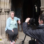 bobby church small Bobby Baker sitting in the sunshine by a church entrance arch being filmed by a camera man