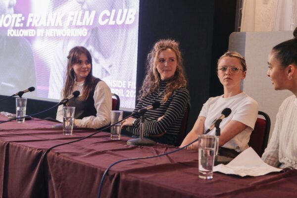 A panel of four people sat at a table with a purple slide projected behind them