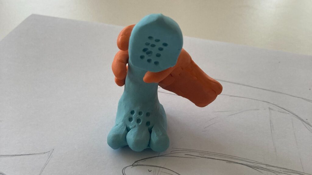 A plasticine model of an orange hand holding a blue phone