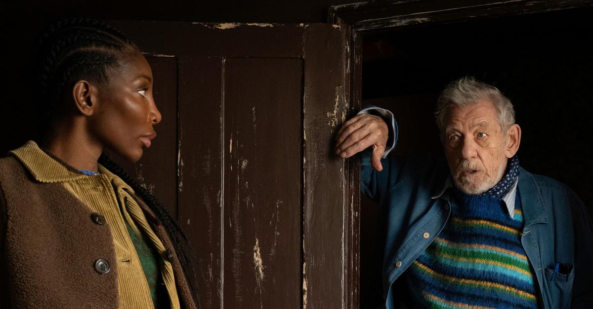 Still from The Christophers of Michaela Coel and Ian McKellen by a dark brown wooden door.