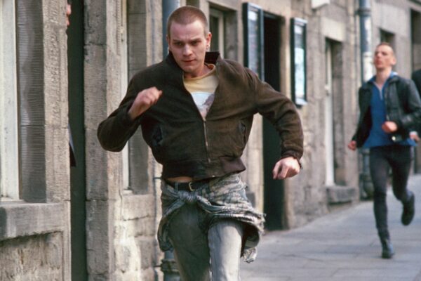 Trainspotting Still - a man running away from two men behind him.
