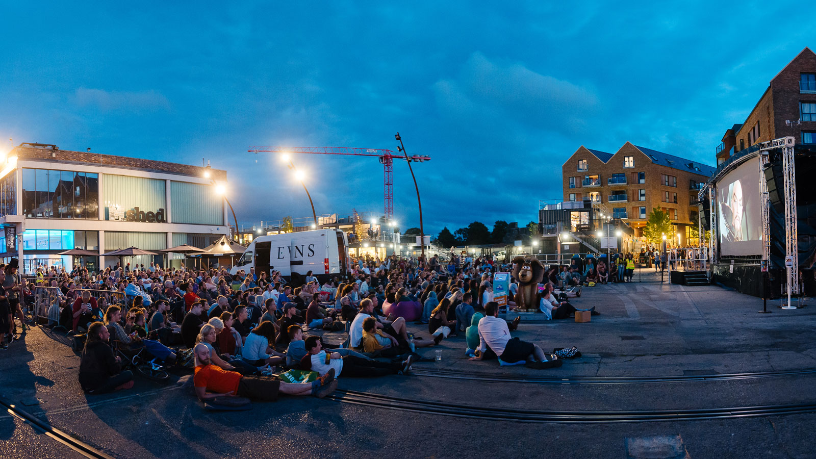 Photo fo people sitting down on Bristol Harbourside watching an outdoor film screening