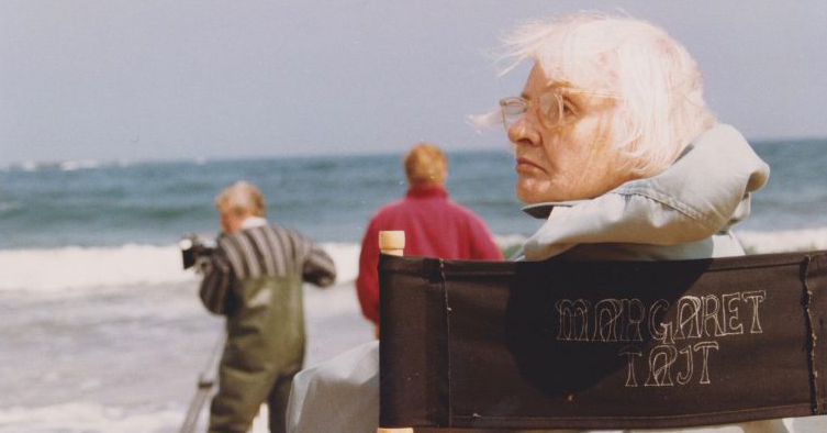 Woman sitting on chair on beach with filmmakers behind her.