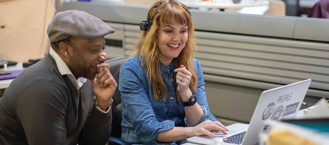 A man and a woman sat working - looking at a laptop