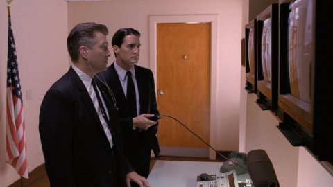 Two men stare at CRT monitors.