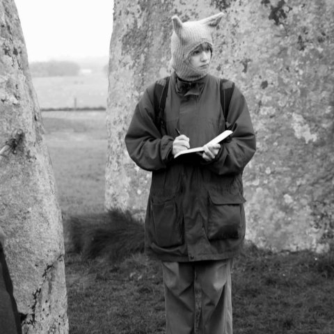 A young turkish woman with a hat with pointy ears looks off to the left, the image is black and white.