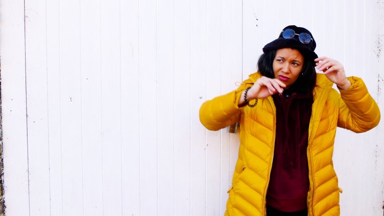 A photo of Deanna Rodger wearing a yellow coat standing against a white background