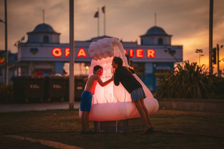 An image of two children hugging a giant illuminated inflatable object.