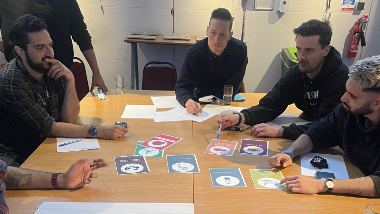 Photo of 4 people sat around a table with coloured A4 subject cards