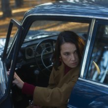 Film still from 1976 of Aline Küppenheim looking at something from her car.