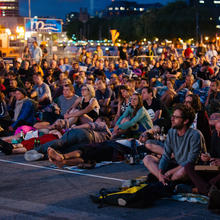 Photo of people sat on the ground watching g a cinema screening in Bristol harbourside