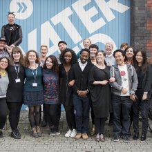 Photo of a group of 20 people standing in front of a Watershed sign at the back of the Watershed building