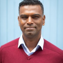 Head shot of man wearing shirt and red jumper