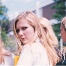 A woman turns to look at the camera, her face quizzical. Three other women walk beside her. 