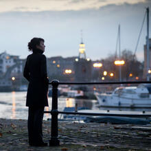 Woman standing on a quayside at sunset.