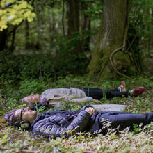 Two people lying down in the woods with headphones on