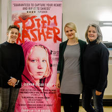 Three women standing with a cinema poster smiling