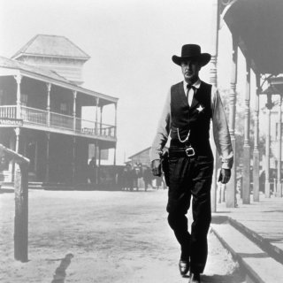 Black and white photo of a sheriff in a stetson striding down a wild west street