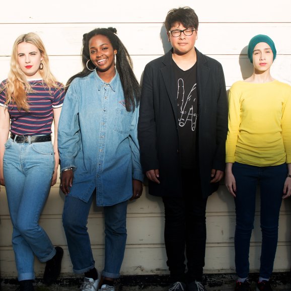 Photo of 4 your people standing against a wall