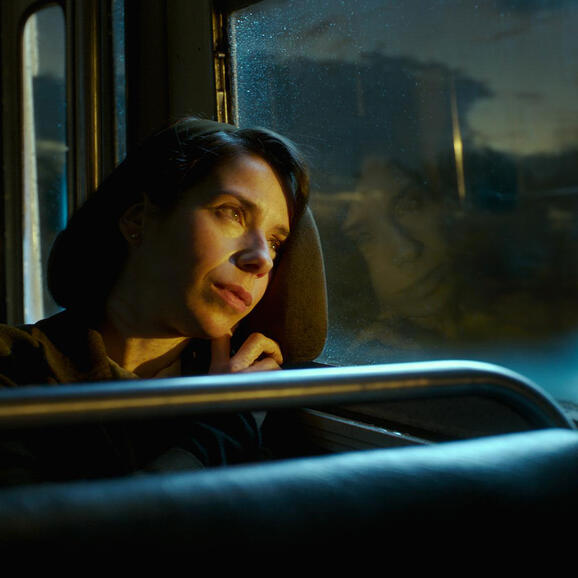 Photo of a woman wistfully looking out on a sunsetting sky from a bus window. From the film The Shape of Water.