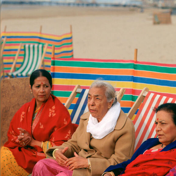 Three women sitting on deckchairs on the beach