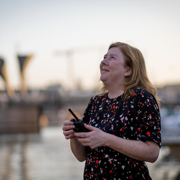 Woman holding a walkie talkie looking up at the sky