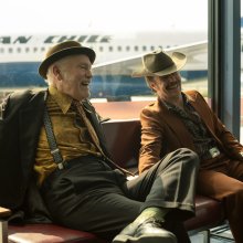 Two men relax and laugh in the departure lounge at an airport,