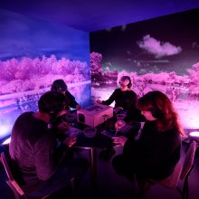 Four people take part in an immersive experience, they are wearing headphones and painting with watercolours.