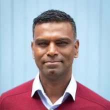 Head shot of man wearing shirt and red jumper