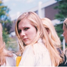 A woman turns to look at the camera, her face quizzical. Three other women walk beside her. 