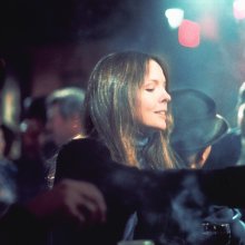 A woman sits alone at a smoky bar.