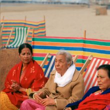 Three women sitting on deckchairs on the beach