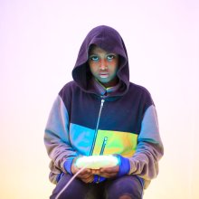 Girl in a hood sitting down holding a glowing light