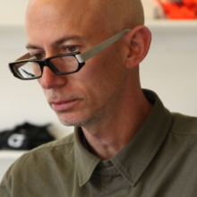 Photo of a man in his fifties wearing glasses and looking downwards