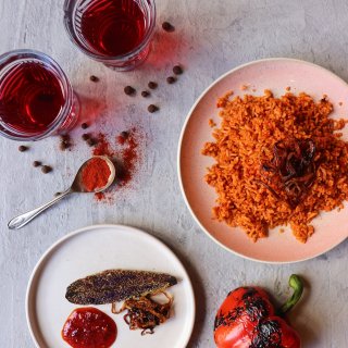 A photo of a dish of spices, two drinks, a plate of food and a charred pepper