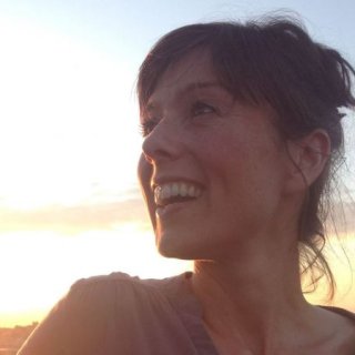 A head shot of Jen Bel against a sunset sky looking in to the distance