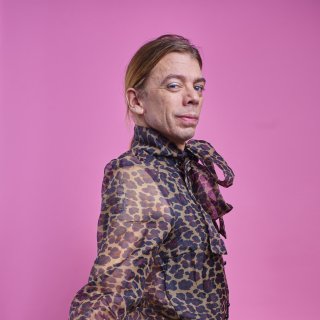 Photo of a man wearing a leopard chiffon shirt against a pink background