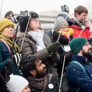 A group of people in Bristol's Millennium Square holding selfie sticks as part of Watershed project Layered Reality